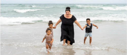 Woman and three children playing in the sea